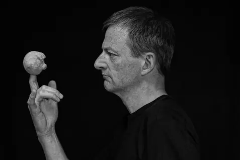 Der Puppenspieler schaut auf seine Handpuppe, der Hintergrund ist schwarz.