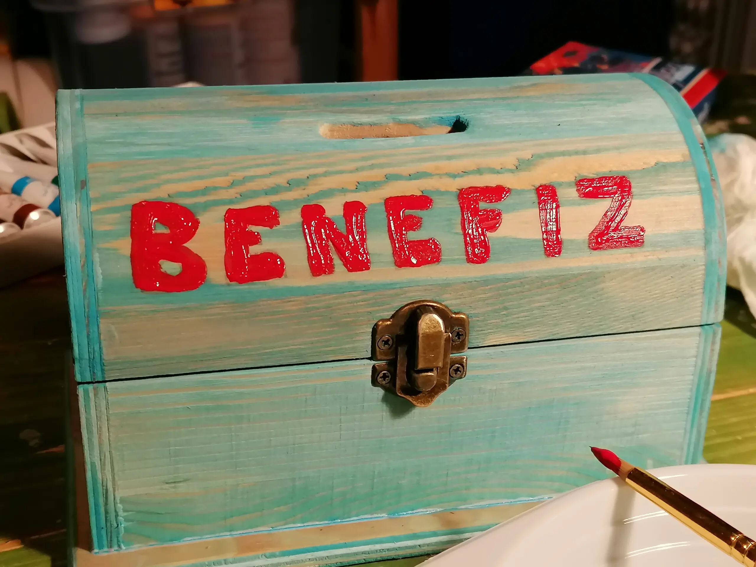 eine blau bemalte Holztruhe mit roten der Aufschrift "Benefiz"