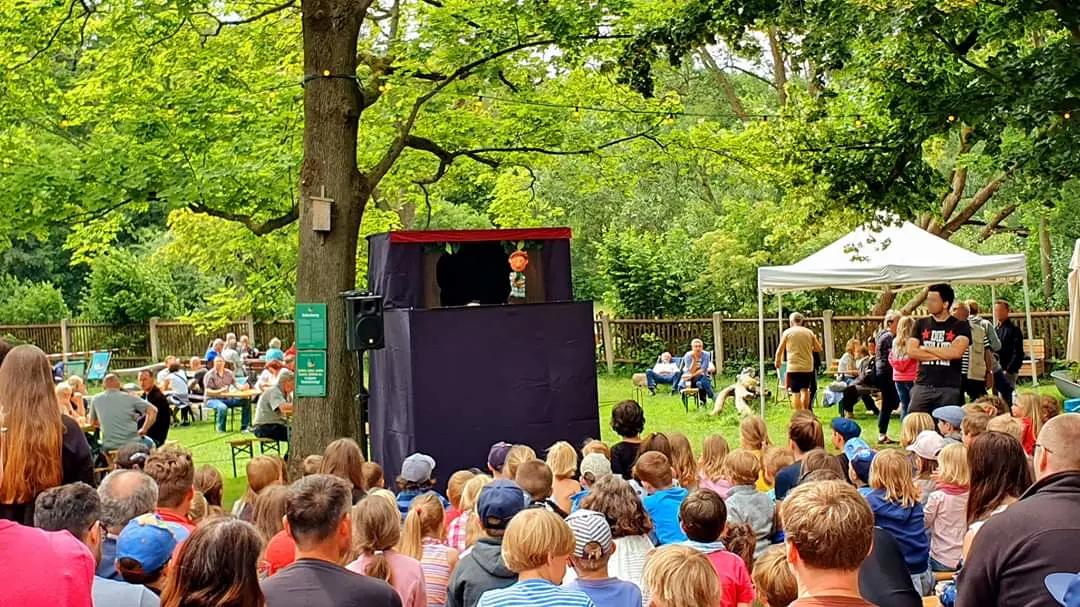 Vor einer schwarzen Puppenbühne sitzen viele Kinder und Familien.